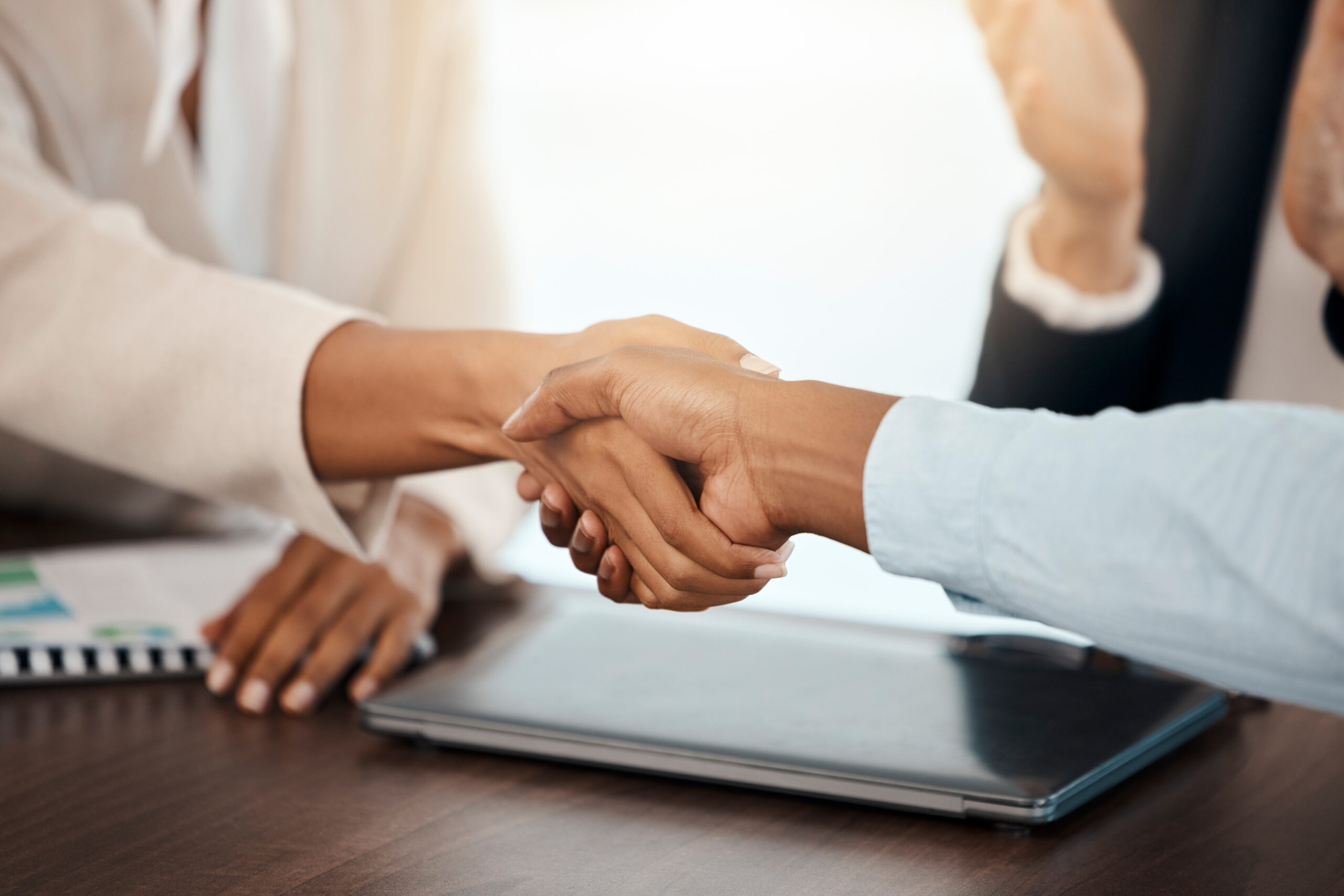 a handshake across a desk between 2 business people